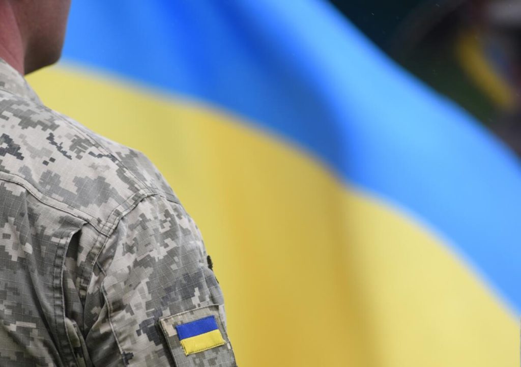 На фото - військовослужбовець та прапор України