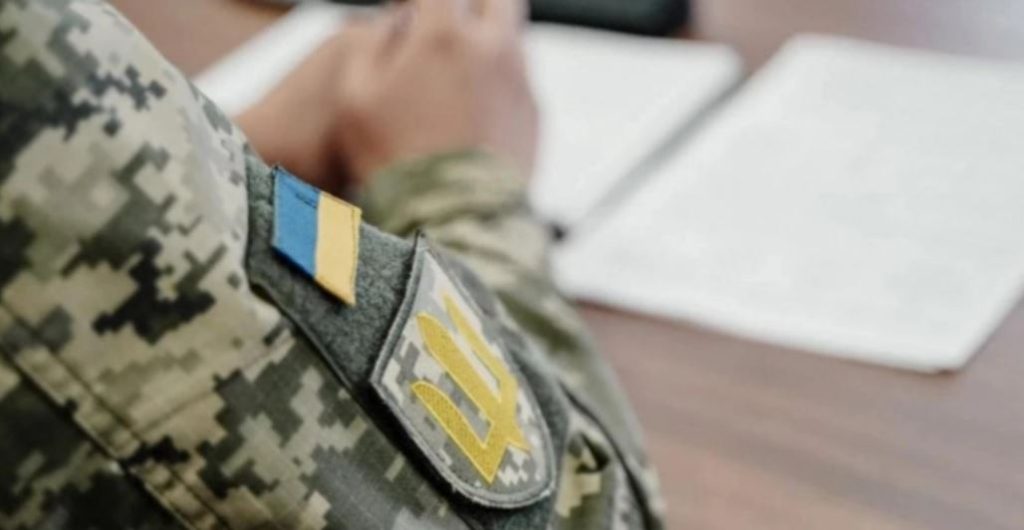 На фото - військовий з шевроном та прапором на плечі